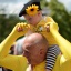 A man wearing the yellow jersey carrying a baby